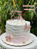Pink and white buttercream round birthday cake with wavy texture, gold pearls, wafer butterflies, and a Happy Birthday topper