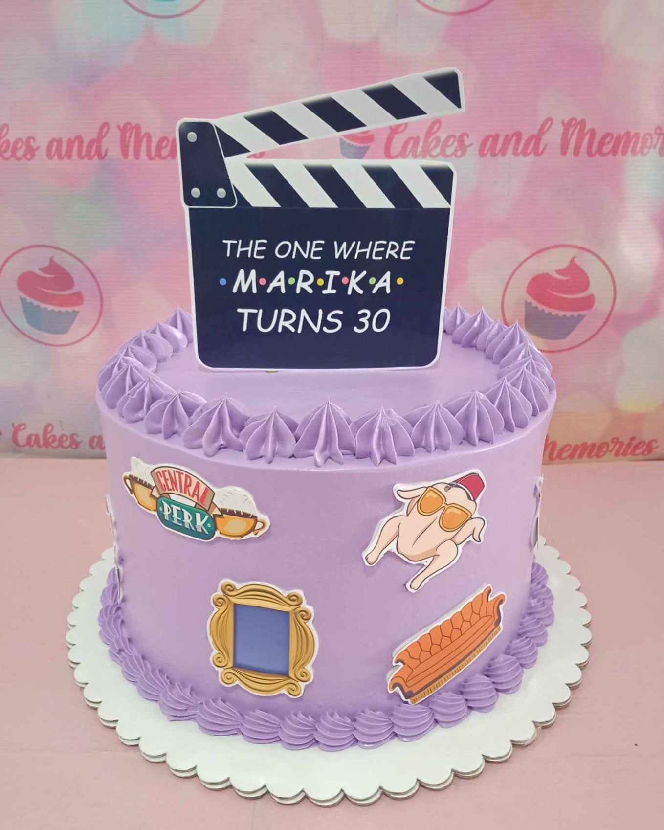 Celebrate a 30th birthday with this whimsical Friends Cake, featuring a vibrant purple color scheme and playful printout toppers inspired by the iconic comedy sitcom. The single-tier design showcases a clapperboard and Central Perk elements, making it a perfect centerpiece for any Friends fan's celebration.