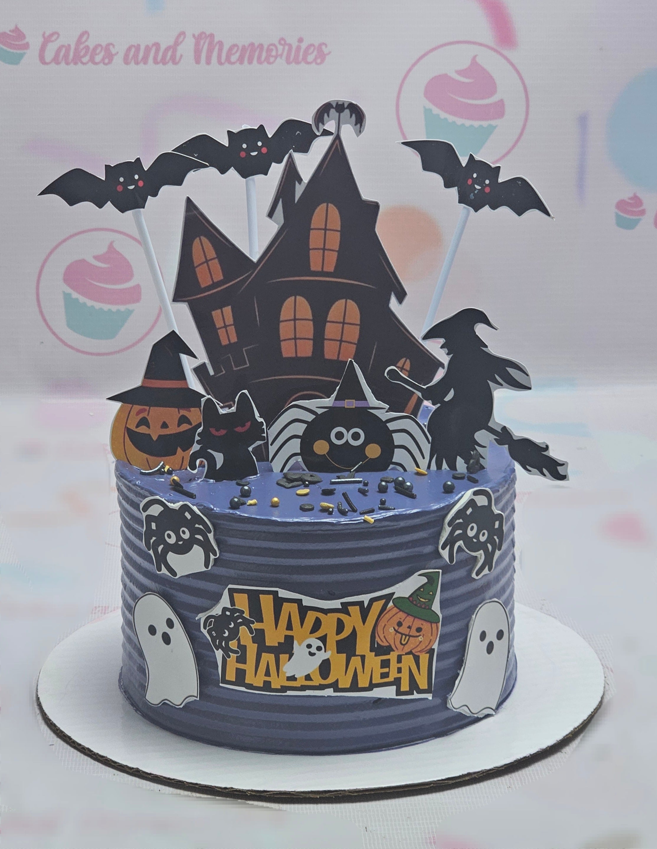 This Happy Halloween Cake features a hauntingly fun design with a purple backdrop, adorned with a spooky haunted house, playful witch, crawling spider, bats, and ghost toppers, along with cheerful pumpkins and festive sprinkles. Perfect for a kid's birthday celebration, this single-layer cake combines scary elements and delightful decorations for a memorable Halloween treat.