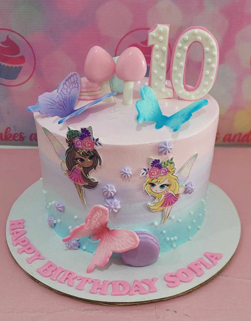 A whimsical pink and blue fairy cake adorned with charming fairies and butterflies perfect for a 10th birthday celebration. This delightful one-tier design captures the magic of Tinkerbell and Winx, making it a great addition to any birthday party.