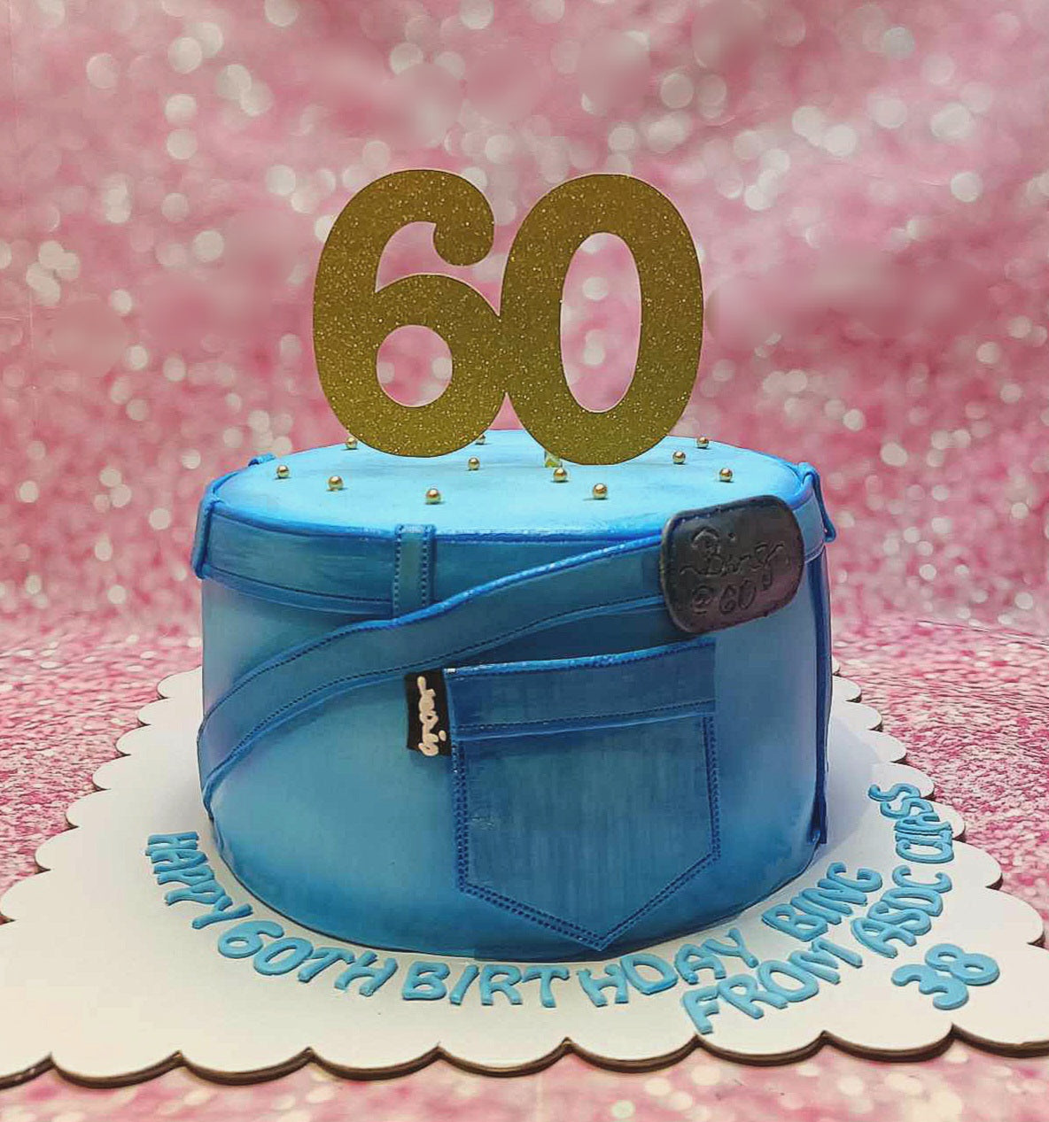 Celebrate a 60th birthday with this stylish Jeans Cake, featuring light blue fondant designed to resemble denim, complete with a jeans pocket and a gold glitter cardstock topper. Perfect for fashion enthusiasts, this one-tier cake is adorned with iconic brand elements like Levi's and Shein.