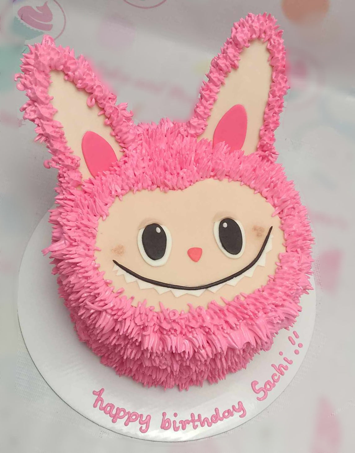 This Labubu Cake features a charming pink design adorned with cute bunny ears and expressive eyes, perfect for Sachi's birthday celebration. The single-tier cake is a trending choice, showcasing fun and vibrant elements.