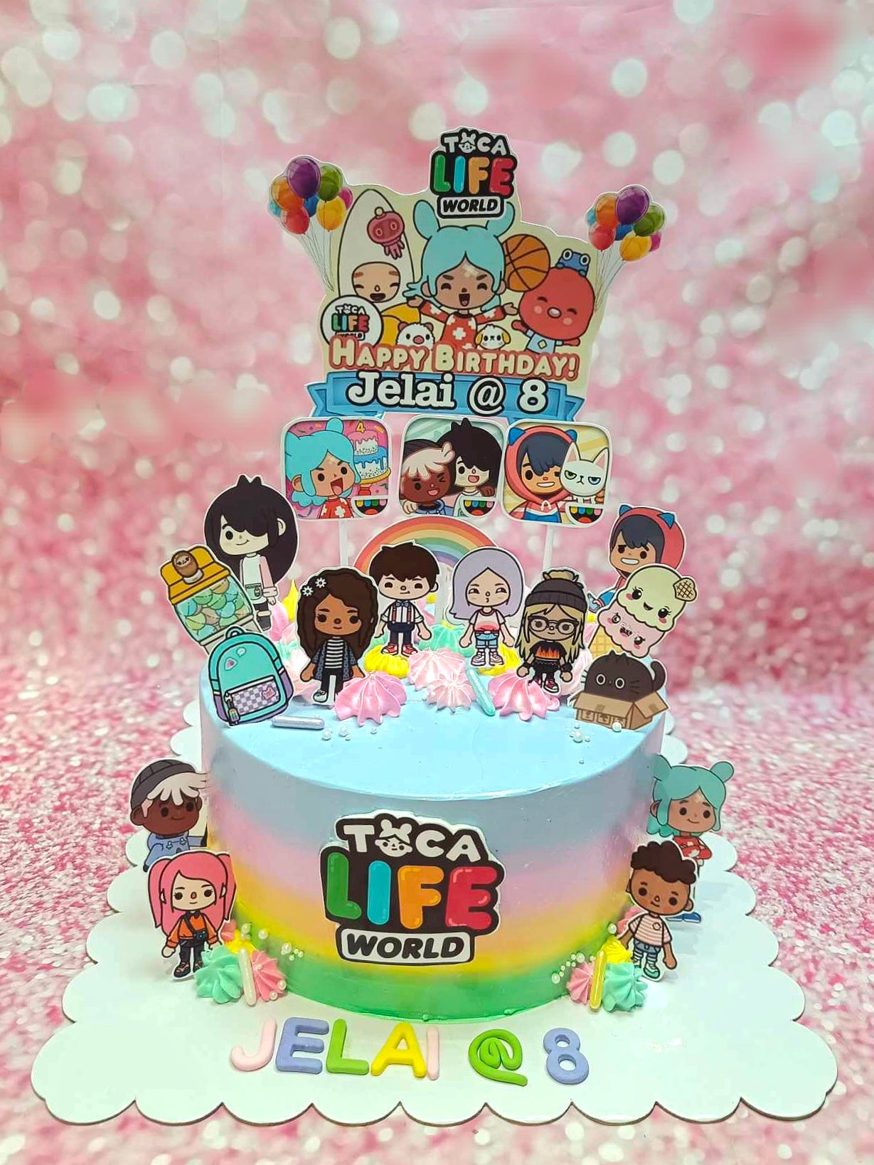 This custom Toca Life Cake features a stunning light blue ombre design, showcasing Toca Life World characters and colorful balloon accents perfect for an 8th birthday celebration. Adorned with rainbow printouts and video game-themed toppers, this one-tier cake is sure to delight!