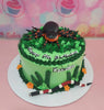 This whimsical Spider Cake features a playful green design with a cute spider and snake atop, perfect for a 7th birthday celebration. Adorned with lush grass and colorful frosting, this one-layer, one-tier cake is an eye-catching centerpiece.