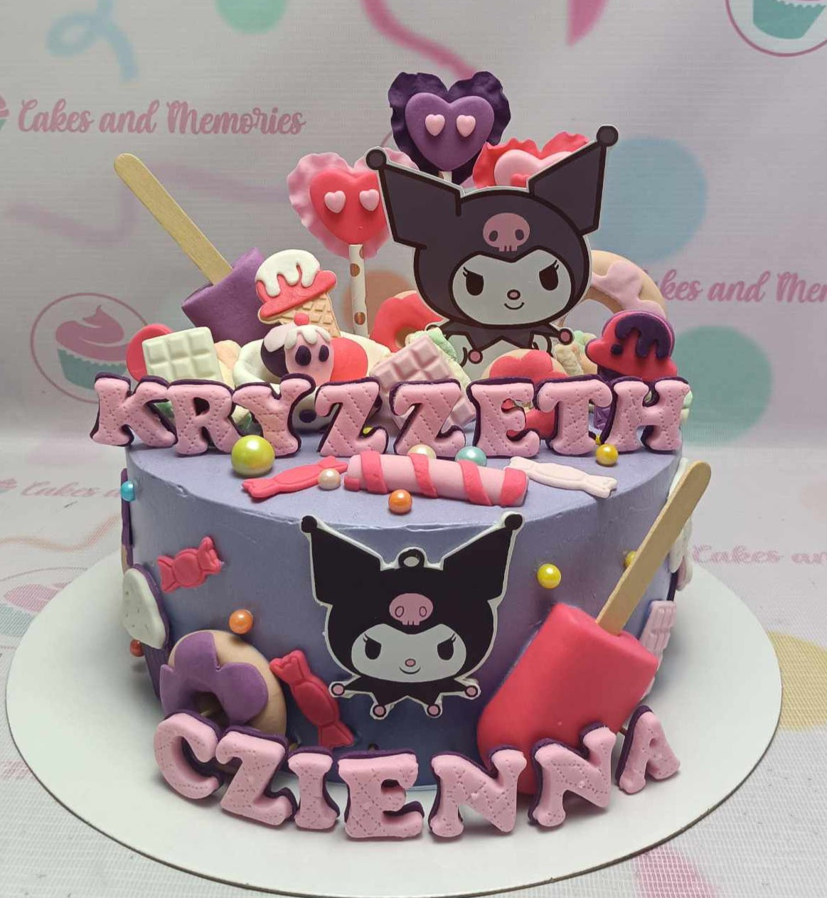 This custom Kuromi cake features a stunning purple design adorned with colorful popsicles, candies, and playful donuts, capturing the essence of Candyland. The cake is topped with ice cream edible toppers and printout toppers of Sanrio characters, making it perfect for fans of Hello Kitty and friends.