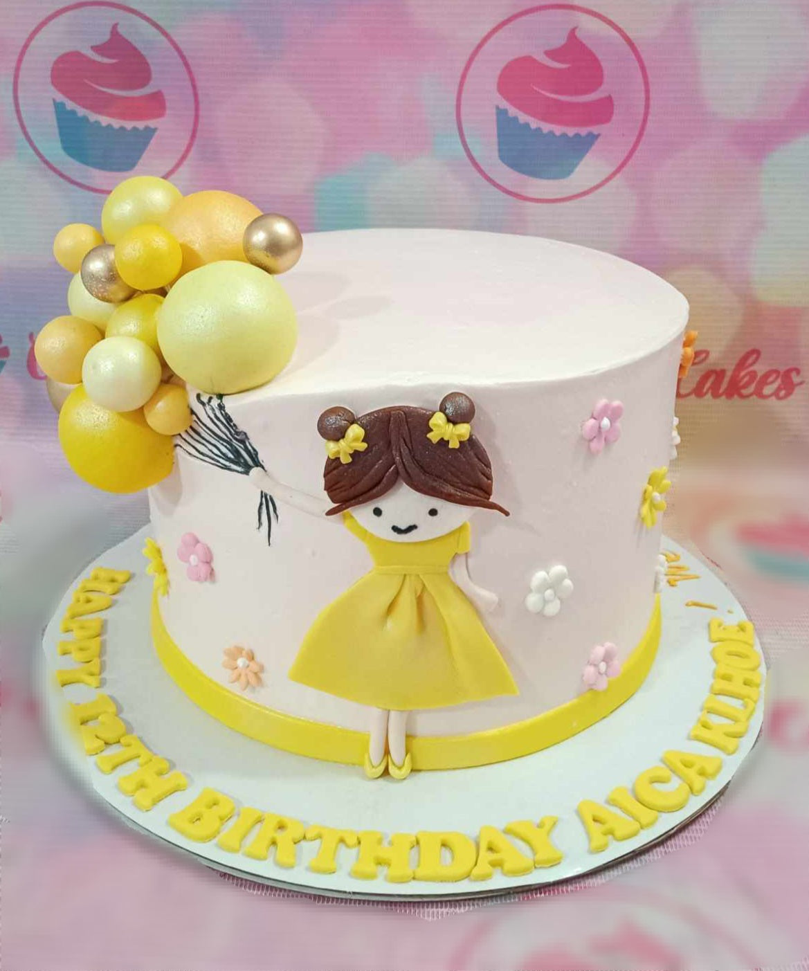 This vibrant Balloon Cake showcases a playful theme featuring a whimsical girl surrounded by bright yellow balloons, silver balls, and adorable printout toppers of Carl and Russell from Pixar's adventure-filled story. The colorful design, set against a backdrop of fluffy clouds and a sky-blue hue, adds a delightful touch to any baby girl's celebration.