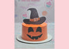 The Scary Pumpkin Witch Cake features a striking orange icing, adorned with a playful witch hat and a cheerful pumpkin, perfect for a Happy Halloween celebration. Custom printout toppers complete this one-tier, one-layer design.