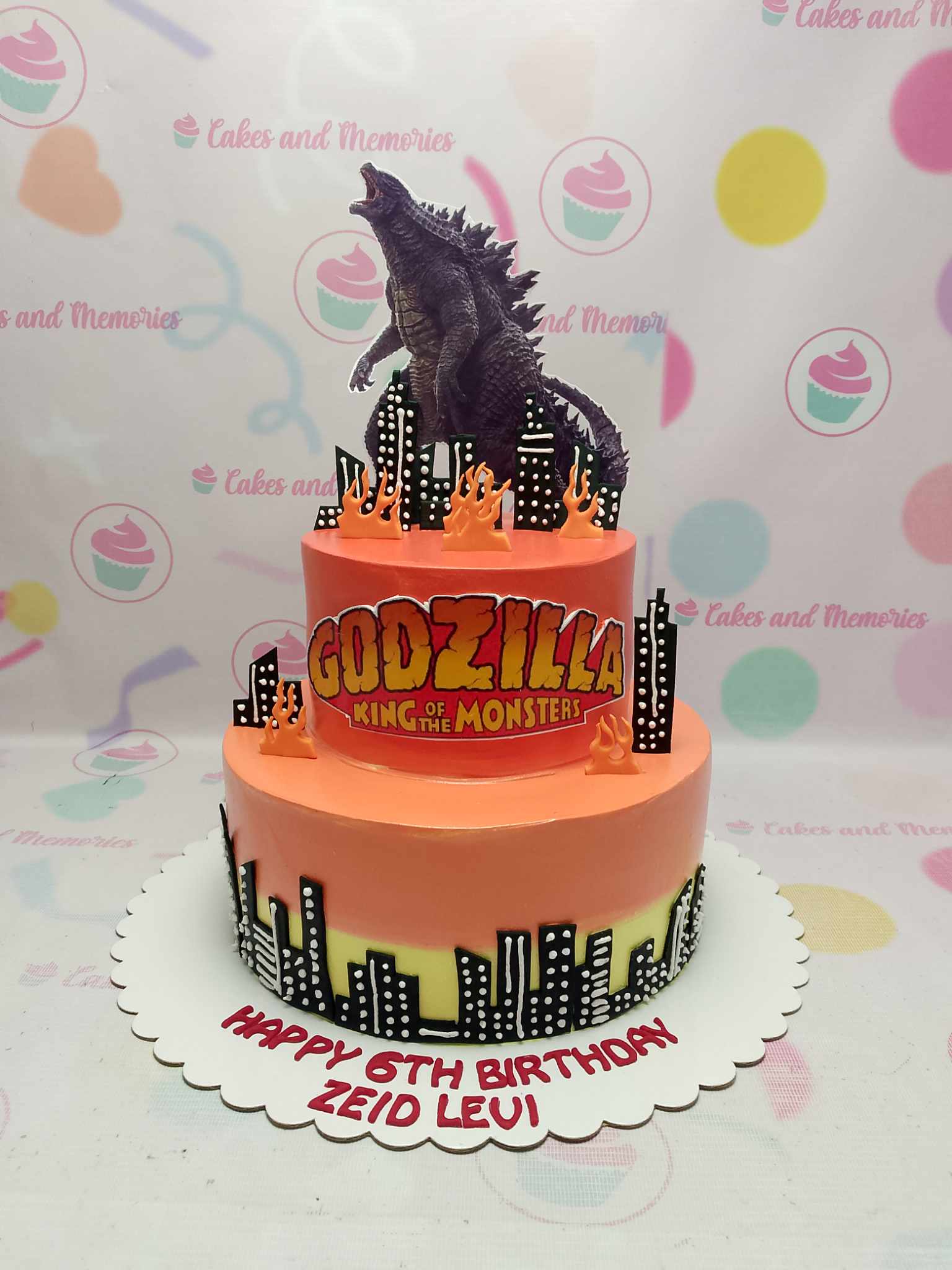 This vibrant Godzilla cake features a striking orange design, capturing the essence of kaiju rampage with fire details and a city backdrop. Adorned with printed toppers, this 2-tiered masterpiece is perfect for any monster-themed birthday celebration.