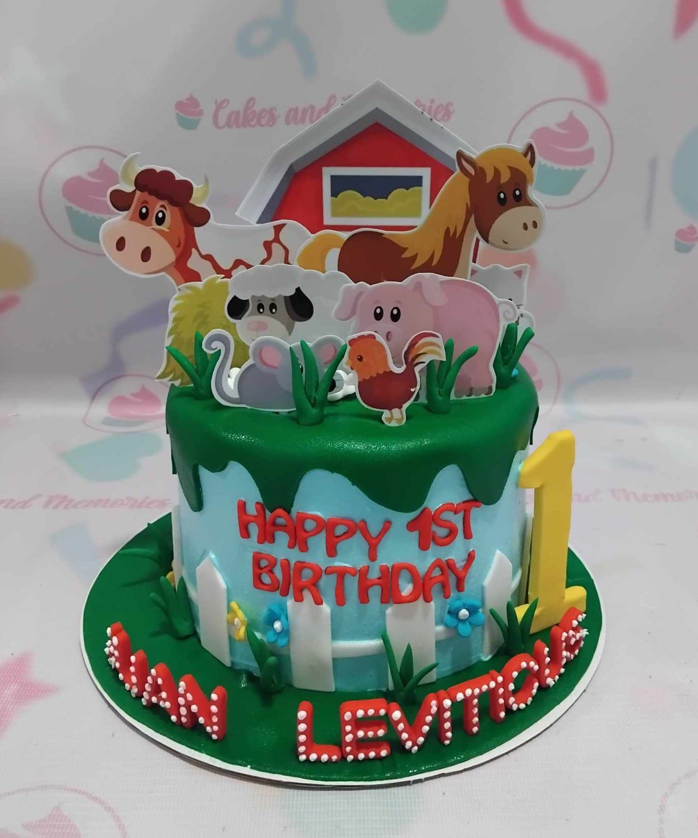 A charming Farm Animals Cake featuring a vibrant blue and green drip, adorned with cute printout toppers of a chicken, pig, cow, and horse, all set against a rustic barn backdrop. This single-tier cake is perfect for a birthday celebration that embraces the farming theme.