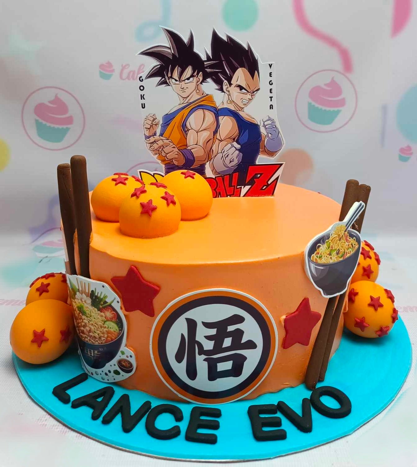 This Dragon Ball Z Cake features Goku and Vegeta with playful orange accents, surrounded by dragonballs, ramen, and chopsticks. Ideal for anime fans, it showcases detailed printout toppers and a fun starry theme on a single tier.