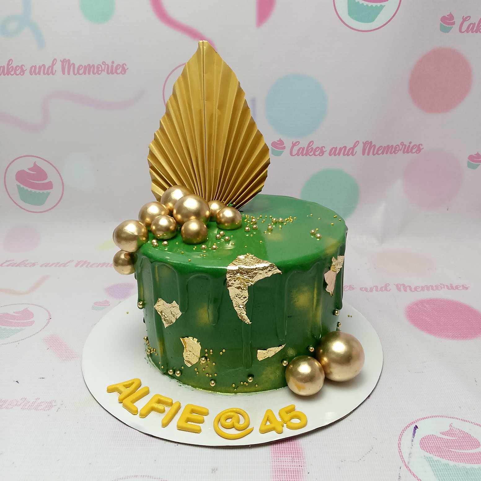 This stunning emerald green drip cake features elegant gold accents, including a golden ball and a gold fan, making it a perfect centerpiece for an 18th birthday celebration. With its chic one-tier design and vibrant green drip, this customized cake is sure to impress.