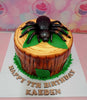 This custom Spider Cake features a detailed fondant design with a brown bark texture and green leaves, perfect for a 7th birthday celebration. Adorned with edible toppers of tarantulas and black widow spiders, it captures the spirit of exotic pets.