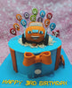 A custom Blippi cake featuring blue icing, a monster truck design, and adorned with colorful rainbow balloons, perfect for a 3rd birthday celebration for Rowan Gabriel. This one-tier cake showcases the number 3 and celebrates the joyful theme of a young boy in a shirt and bow tie.