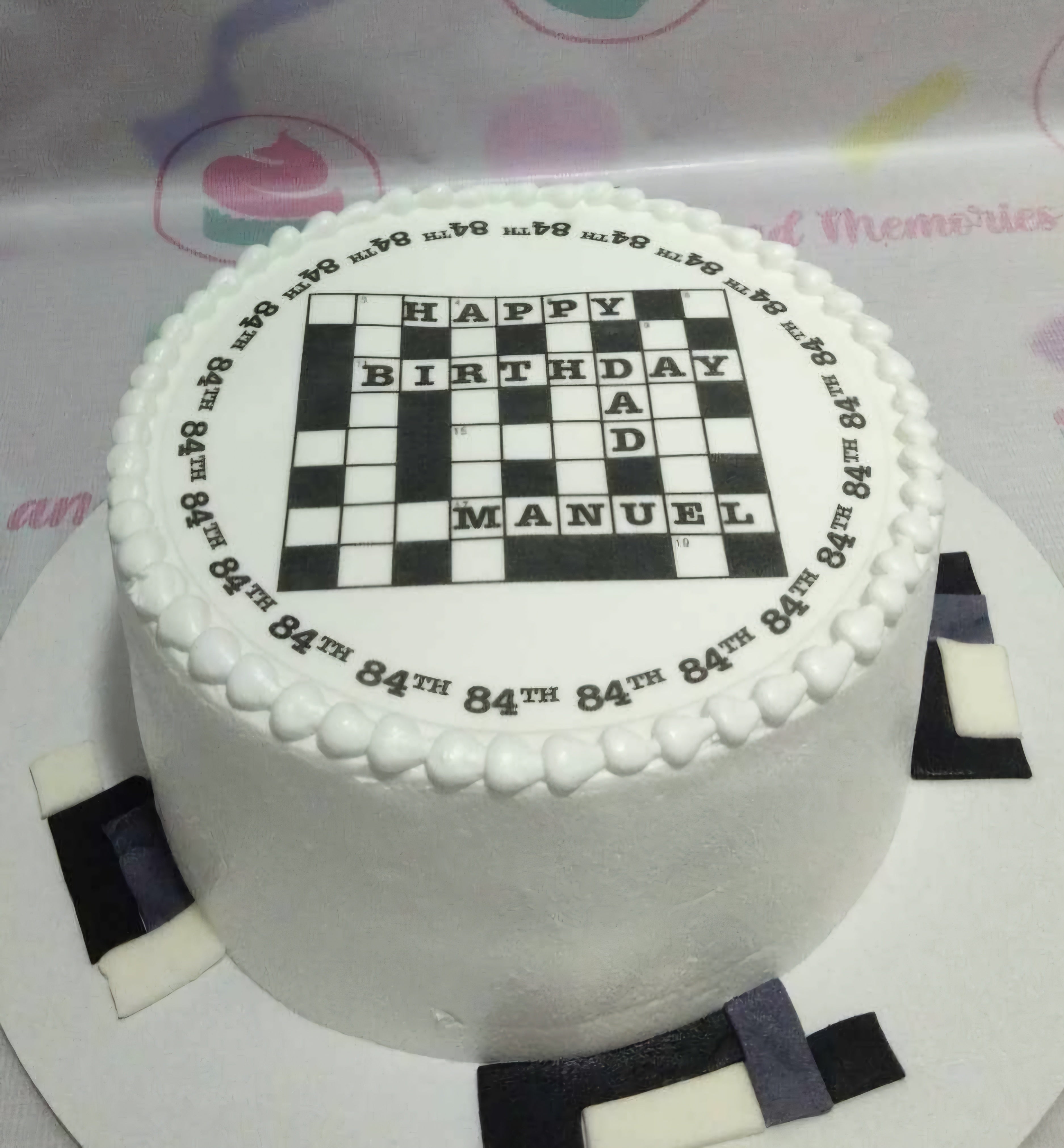 A stunning Crossword Puzzle Cake featuring a sleek black and white design with edible printed words that create an engaging puzzle effect. This one-tier, one-layer creation is perfect for puzzle enthusiasts and makes a memorable centerpiece for any occasion.