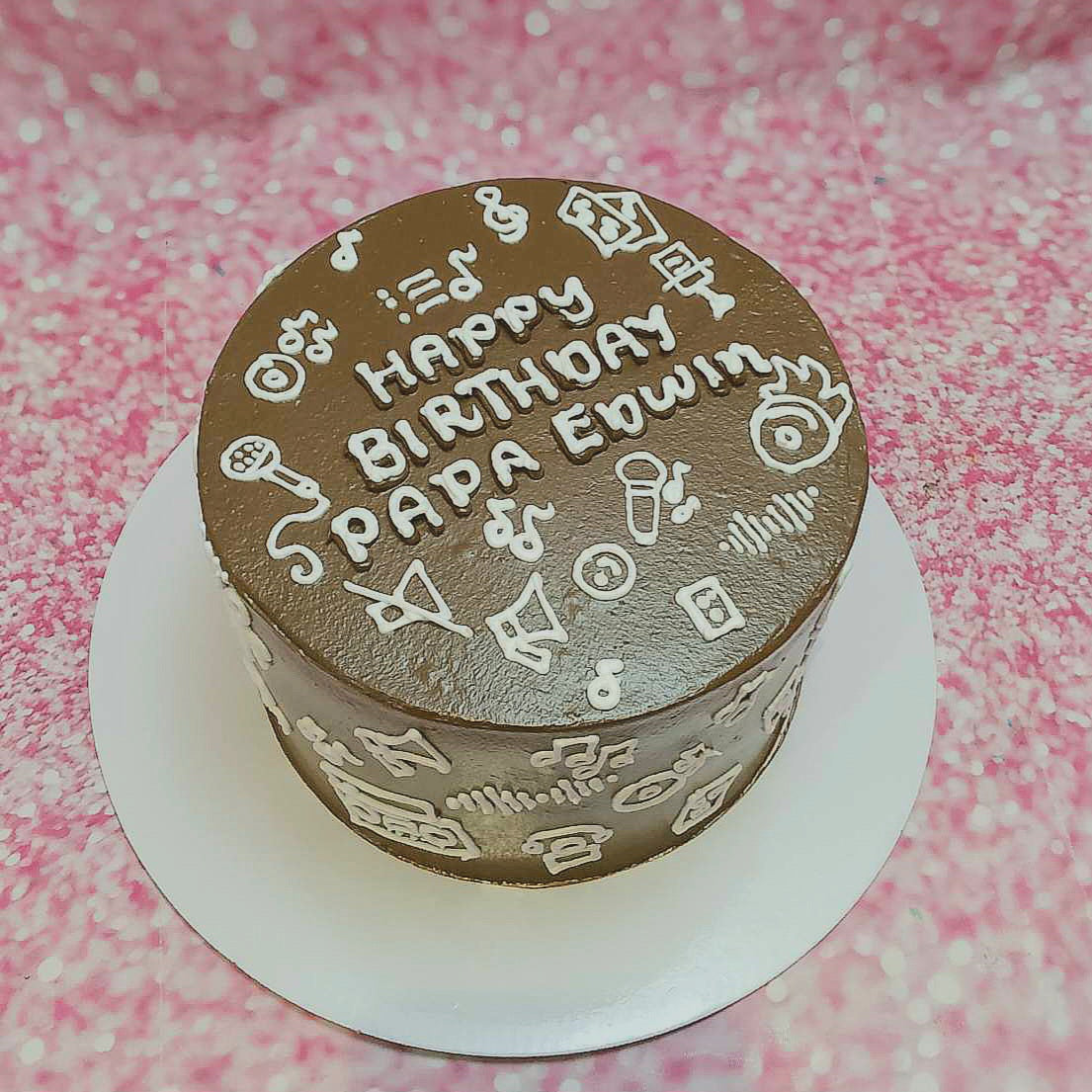 A custom-designed brown Music Cake features charming hand-drawn doodles of musical notes, microphones, and speakers, celebrating Papa Edwin as a rockstar for tito, brother, dad, and lolo. This single-layer, one-tier cake is perfect for any musician.