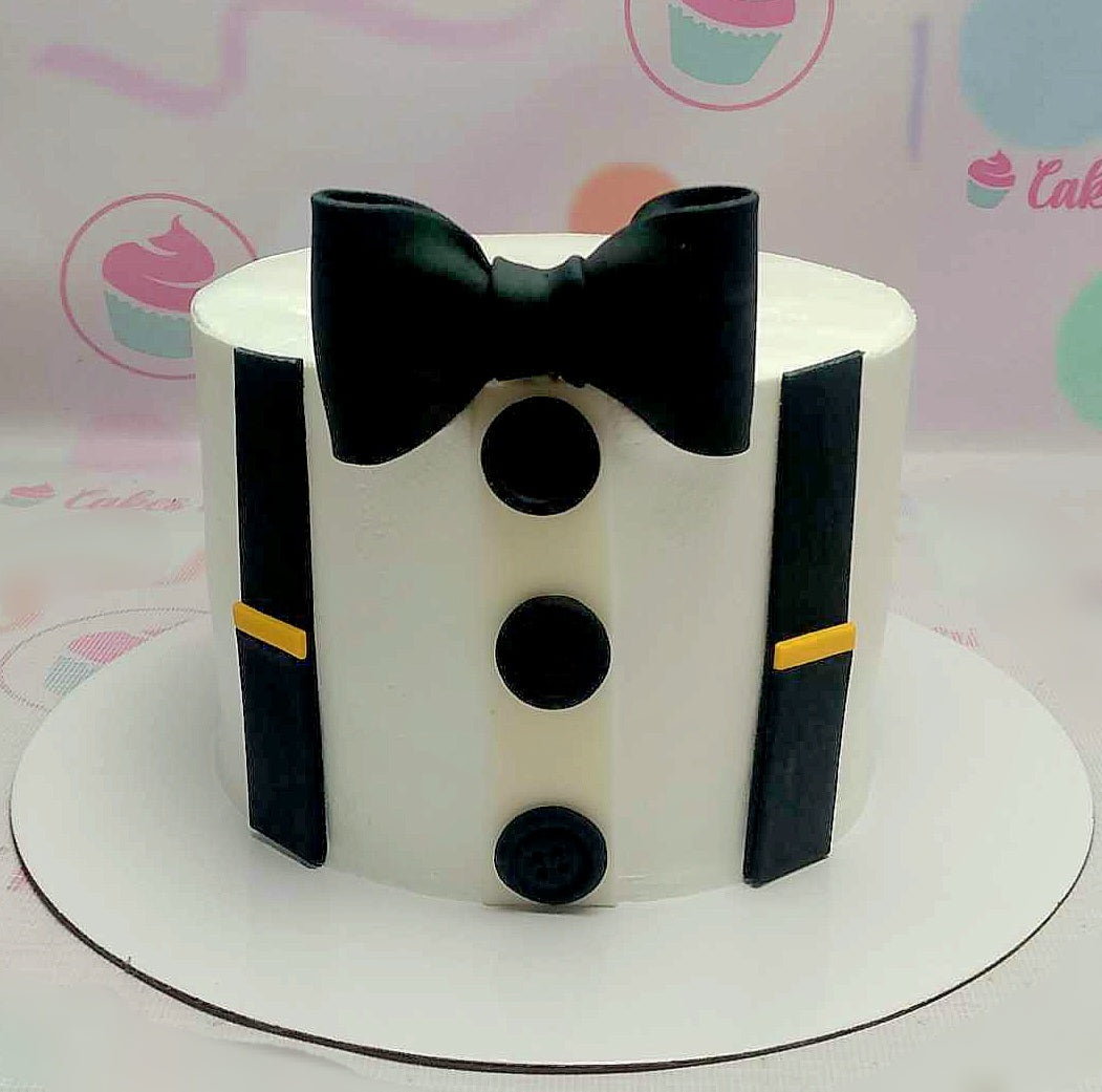 This elegant white suit cake features a detailed tuxedo design with a bow tie, buttons, and suspenders, complemented by gold accents. Perfect for prom or a businessman’s celebration, this charming 1-tier cake captures the essence of sophistication.