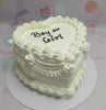 A classic vintage design heart-shaped cake in white, featuring elegant frills and swirls, perfect for a boy or girl gender reveal. This one-tier cake, adorned with a charming bow, makes a delightful centerpiece for any baby celebration.