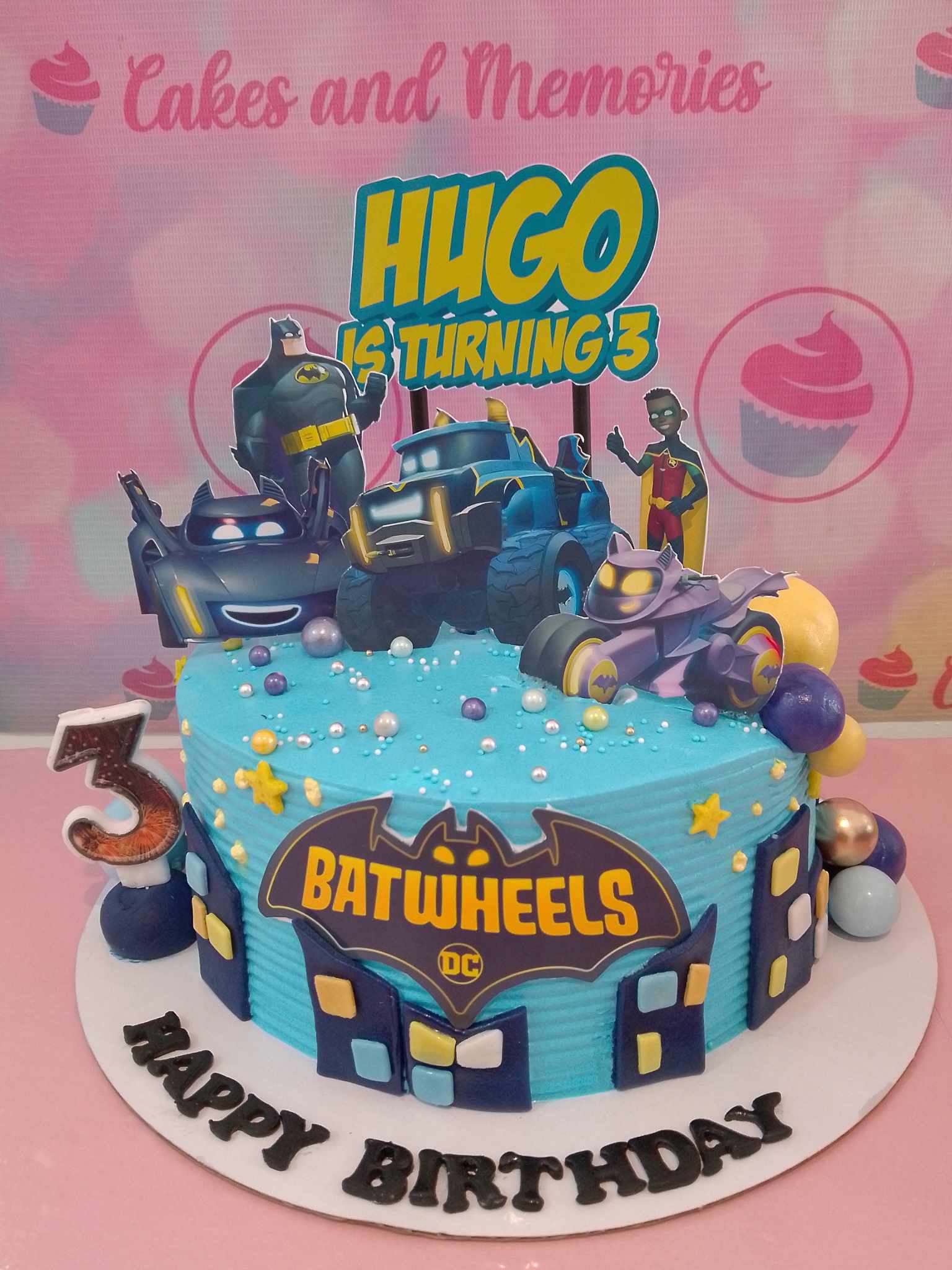 This custom Batman cake features a playful design with blue accents, showcasing batwheels, Robin, Nightwing, and the iconic Batmobile, perfect for a 3rd birthday celebration. Ideal for young superheroes, this 1-tier cake captures the spirit of DC cartoons and the Justice League.