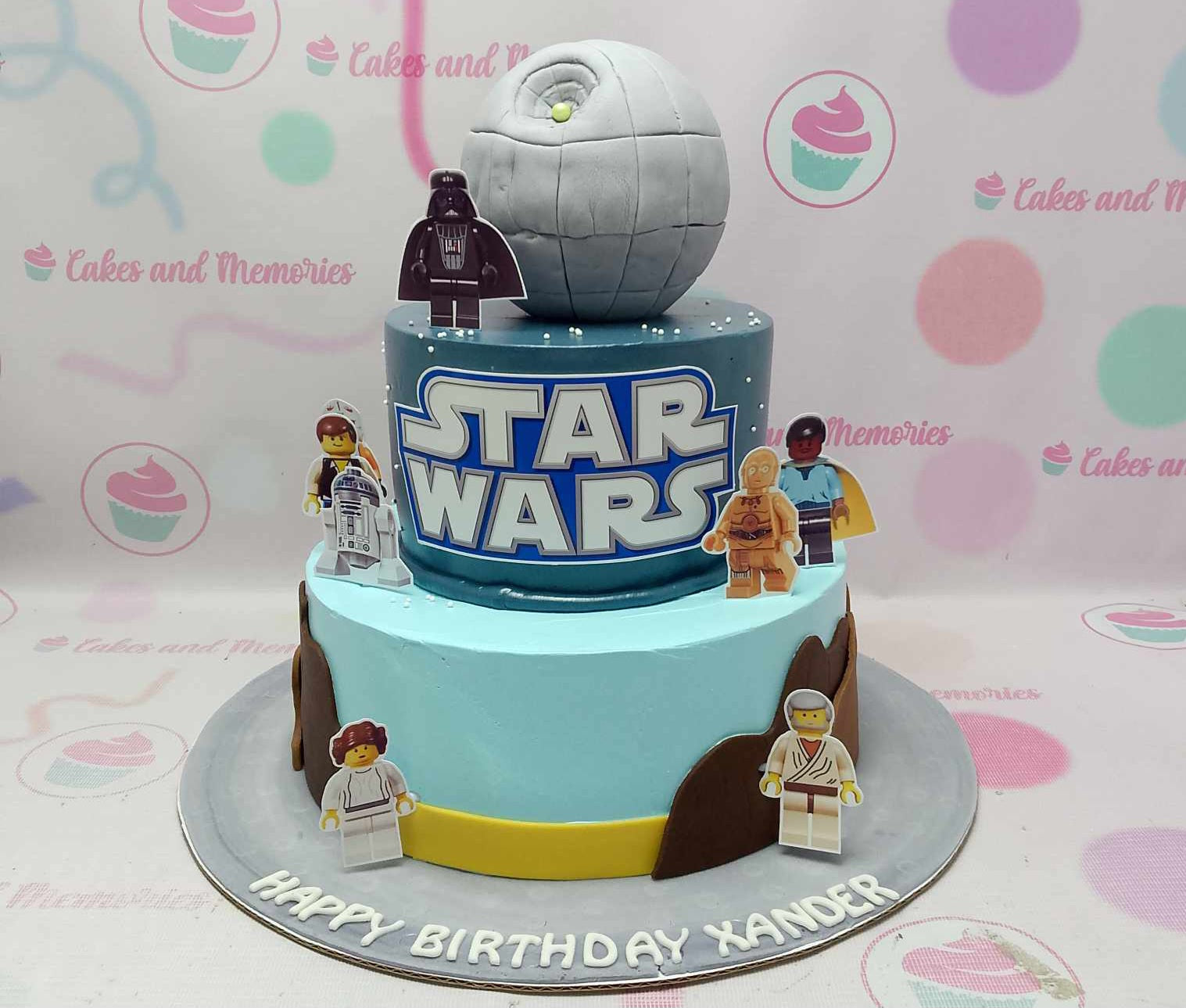 Introducing our stunning Star Wars Cake, featuring a vibrant blue design with a detailed edible Death Star topper, alongside iconic characters Darth Vader and Luke Skywalker. This impressive two-tiered creation is perfect for any Star Wars fan's birthday celebration!