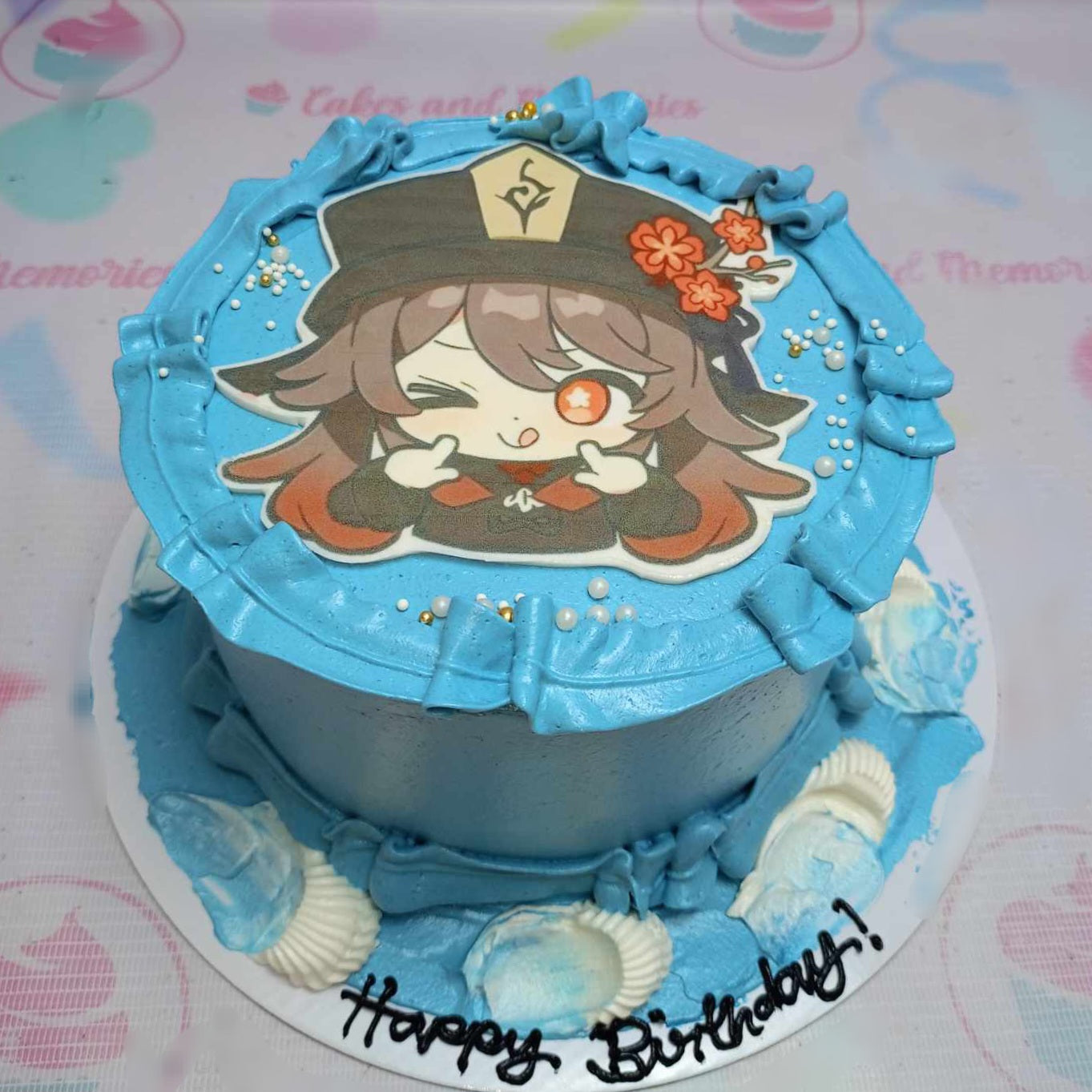 A stunning Genshin Impact cake featuring a vibrant blue design with chibi Hu Tao emotes and edible photo print toppers. This custom one-tier cake is perfect for video game enthusiasts celebrating a birthday.