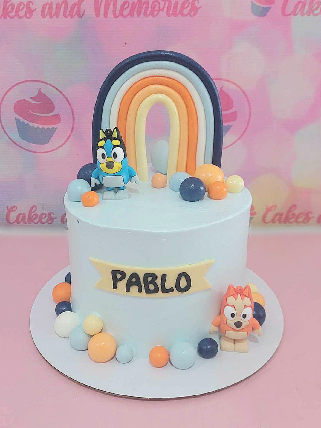 Celebrate a birthday with a vibrant Bluey cake featuring colorful balls and adorable printout toppers of Bluey and Bingo. This whimsical 1-tier design showcases the name Pablo, bringing the beloved Australian cartoon to life for your little one.