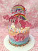This charming My Little Pony cake features pastel ombre icing with playful elements like Pinkie Pie, a castle, and colorful rainbow details. Sprinkled with hearts and topped with printout toppers, it's a delightful centerpiece for any birthday celebration.