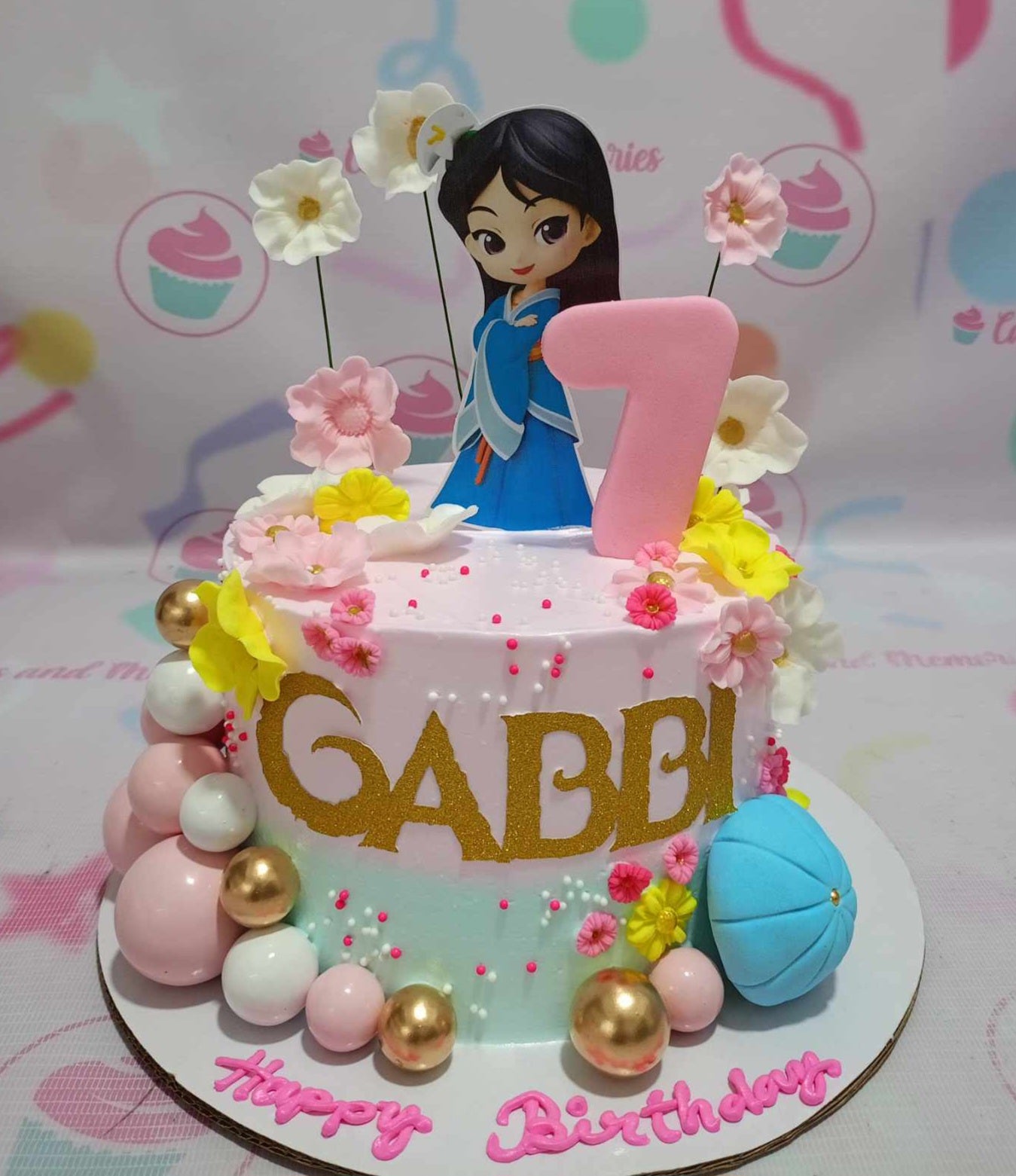 Showcase your celebration with this stunning Mulan Cake featuring vibrant pink and green colors. Adorned with a chibi printout topper, gold glitter name, and playful pink and golden balls, this one-tier masterpiece brings a touch of magic to any occasion.