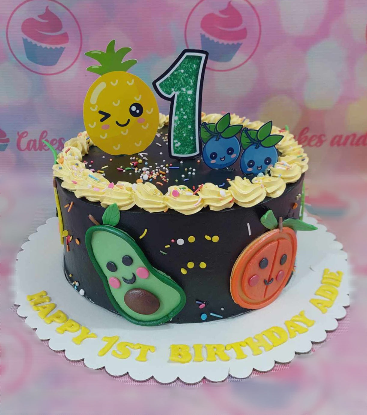 This vibrant Fruits & Veggies Cake features a whimsical design with fresh pineapple, blueberries, avocado, and orange adorning a beautifully decorated round cake. Topped with luscious chocolate frosting, sprinkles, and custom printout toppers, this one-tier birthday cake is a delightful centerpiece for any celebration.