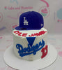 This custom baseball cake features a single tier adorned with white and blue accents inspired by the LA Dodgers, perfect for celebrating a 13th birthday. The design captures the spirit of the World Series and MLB, making it a memorable centerpiece for any young fan.