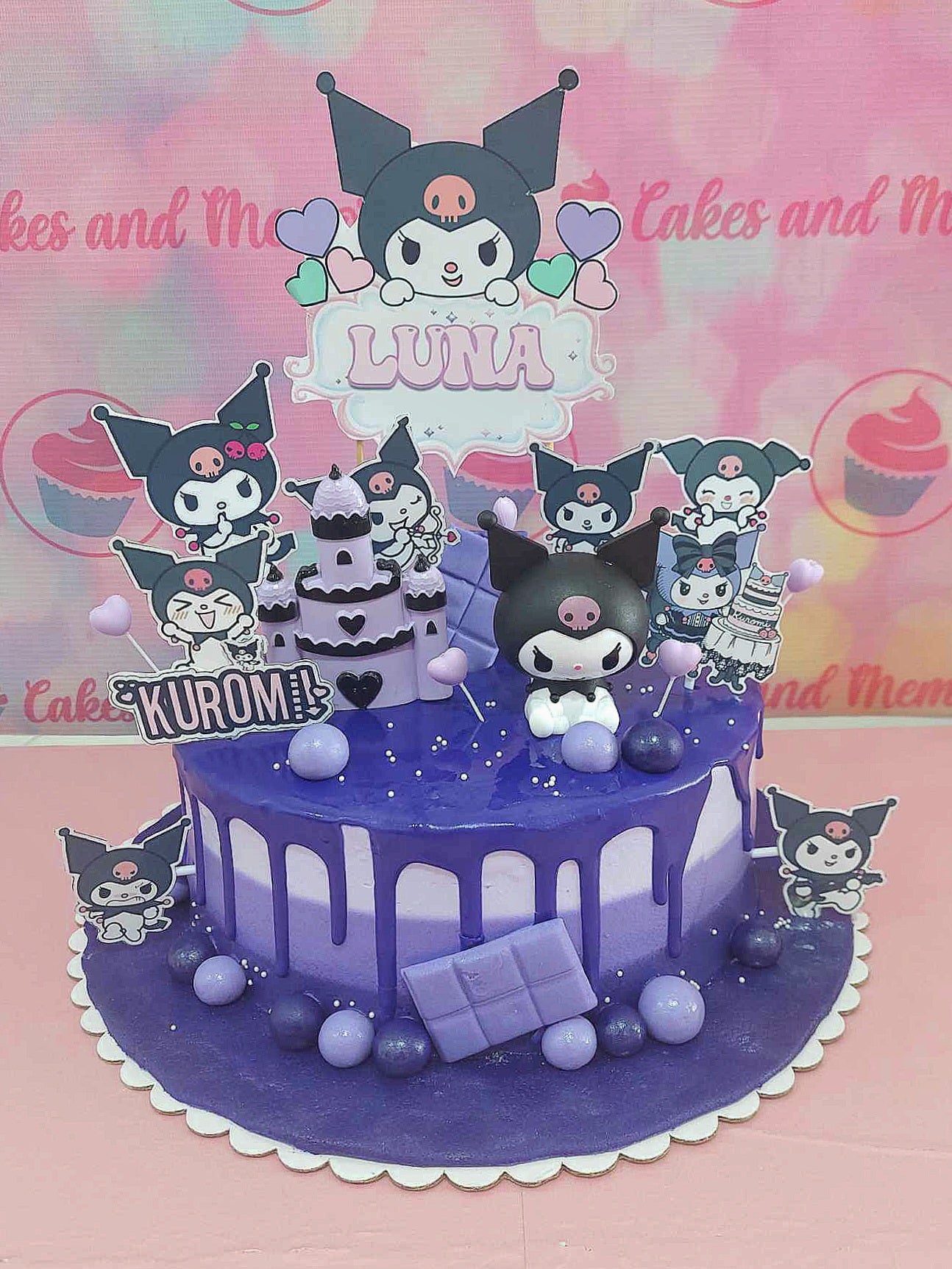 This Kuromi Cake features a stunning ombre purple design with a black dripping effect, decorated with cute cartoon printout toppers and an enchanting castle. Layered and adorned with candy and chocolate accents, it perfectly captures the kawaii essence of Sanrio characters like Kuromi and My Melody.