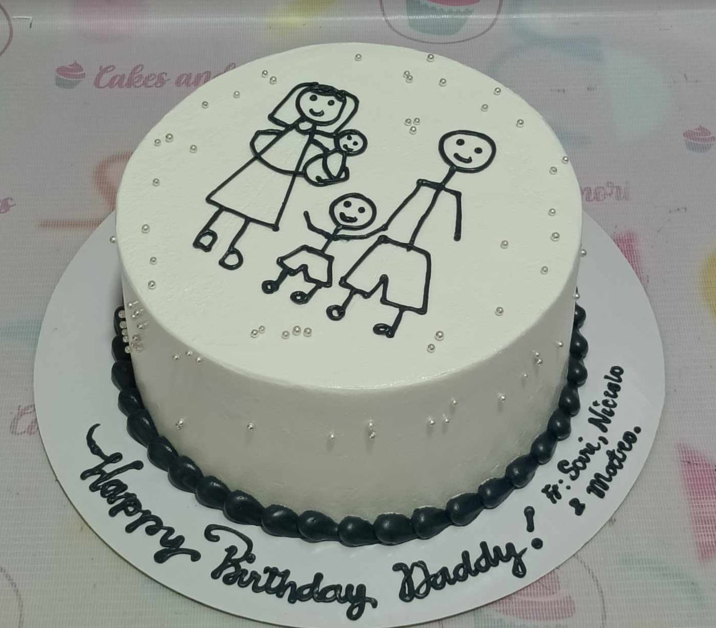 This delightful Doodle Cake features a clean white design adorned with playful stick figures representing a family, celebrating "Happy Birthday Daddy." The 1-tier, 1-layer cake is topped with charming drawing-style printout toppers, capturing the essence of a loving father and family.