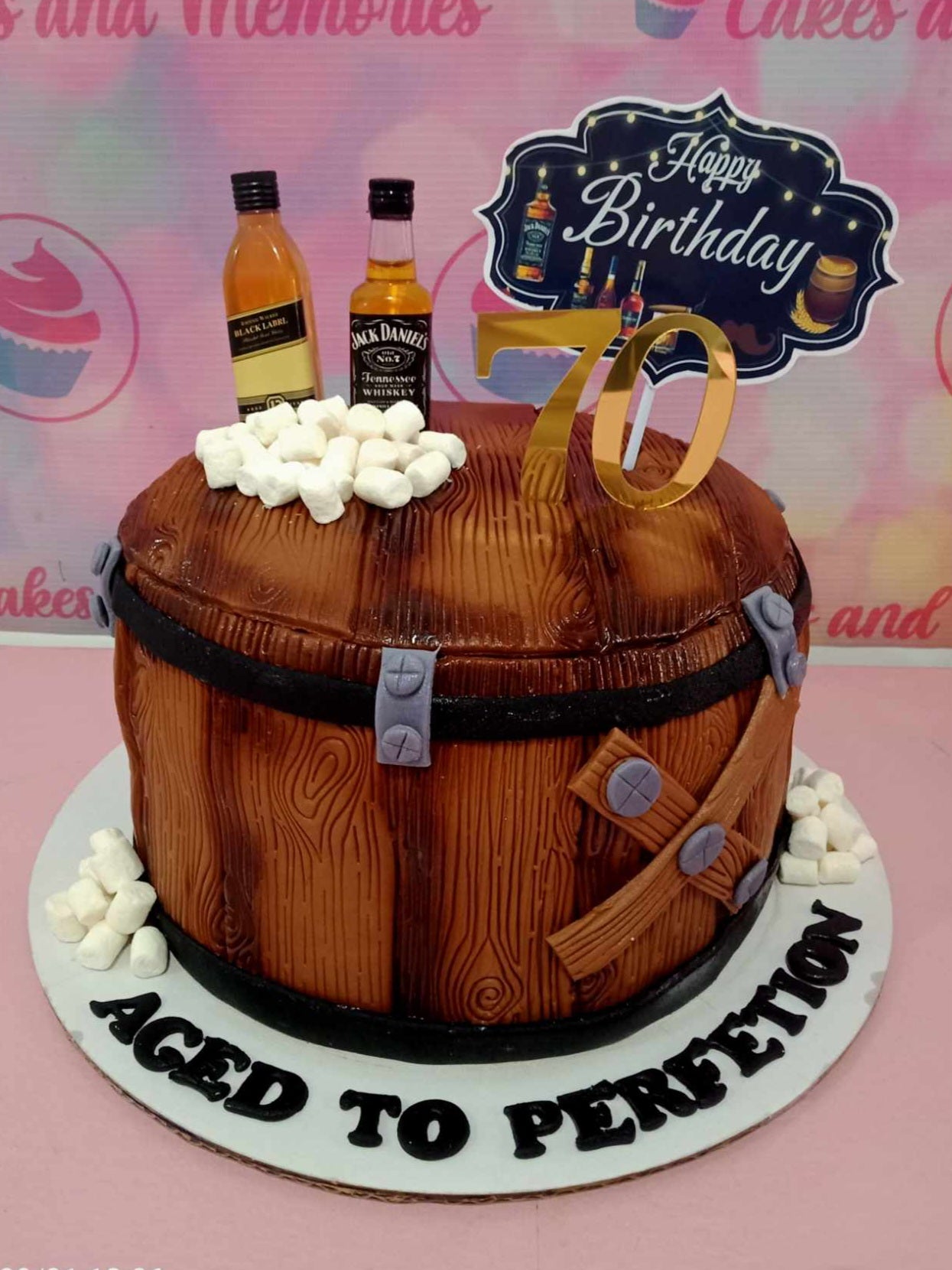 This custom Drinks Cake features a stunning wood barrel design, complete with miniature whiskey bottles and marshmallows, perfect for celebrating a 70th birthday for a beloved grandad. The refined details and aged perfection elements make it an ideal tribute for any gentleman in your life.