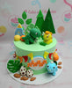 This charming Dinosaurs Cake features a lush green backdrop adorned with edible dinosaur toppers, including a triceratops, surrounded by trees, leaves, dino eggs, and rocks, perfect for a 4th birthday celebration. It stands as a delightful 1-tier design, showcasing a fun prehistoric theme.