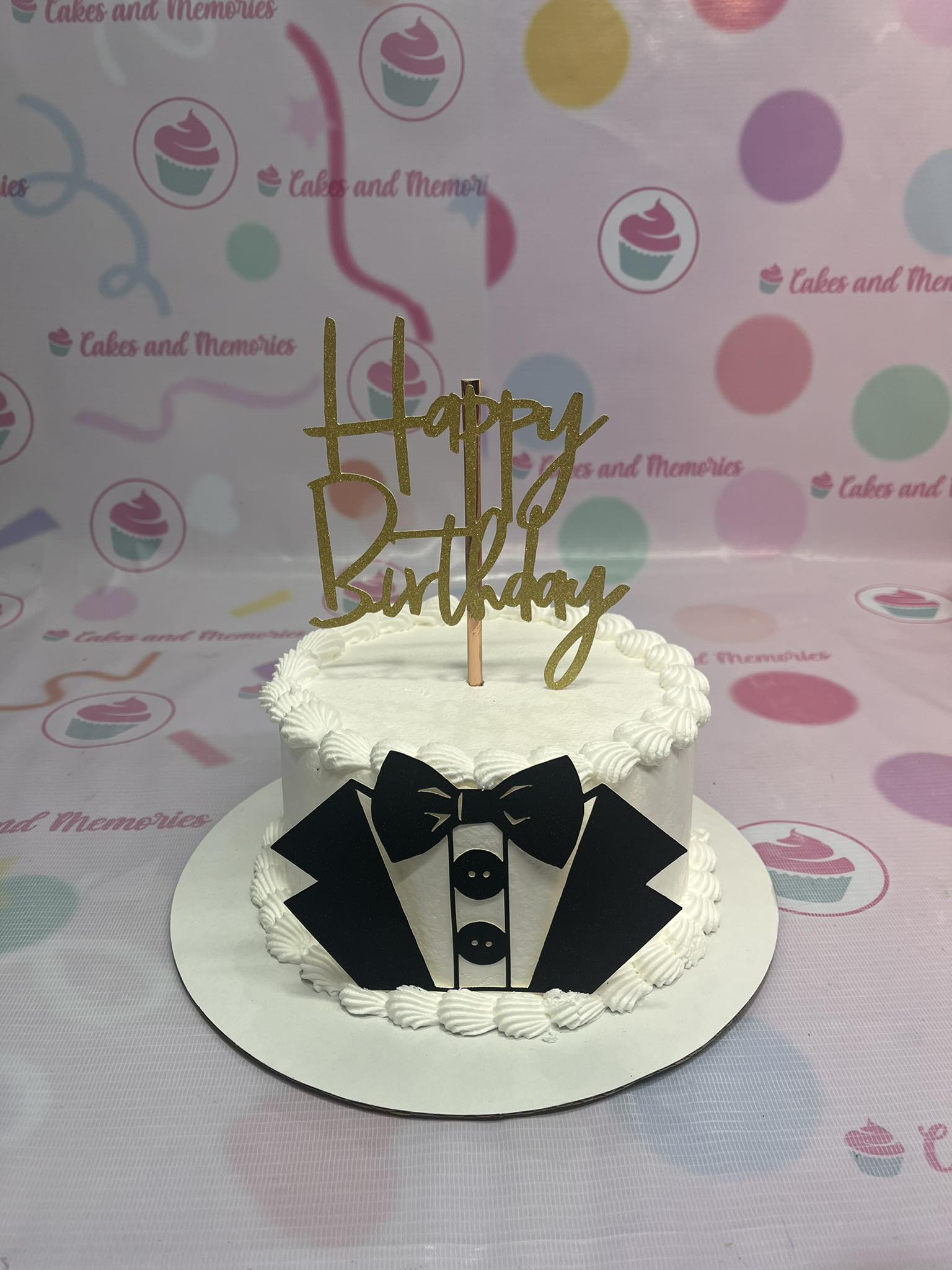 This custom Suit Cake features a classic white tuxedo design with a stylish bowtie and decorative buttons, perfect for celebrating a birthday for a man, dad, brother, grandfather, or papa. Adorned with printout toppers, this one-tier cake is a charming centerpiece for any special occasion.