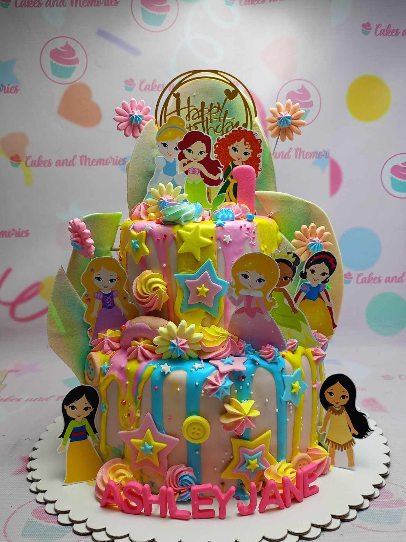 This enchanting 2-tier Princess Cake features pastel pink and blue  Fondant, adorned with vibrant printout toppers of beloved Disney princesses like Cinderella, Aurora, and Ariel. Perfect for a baby birthday celebration, this customized cake is a royal treat for any little princess.