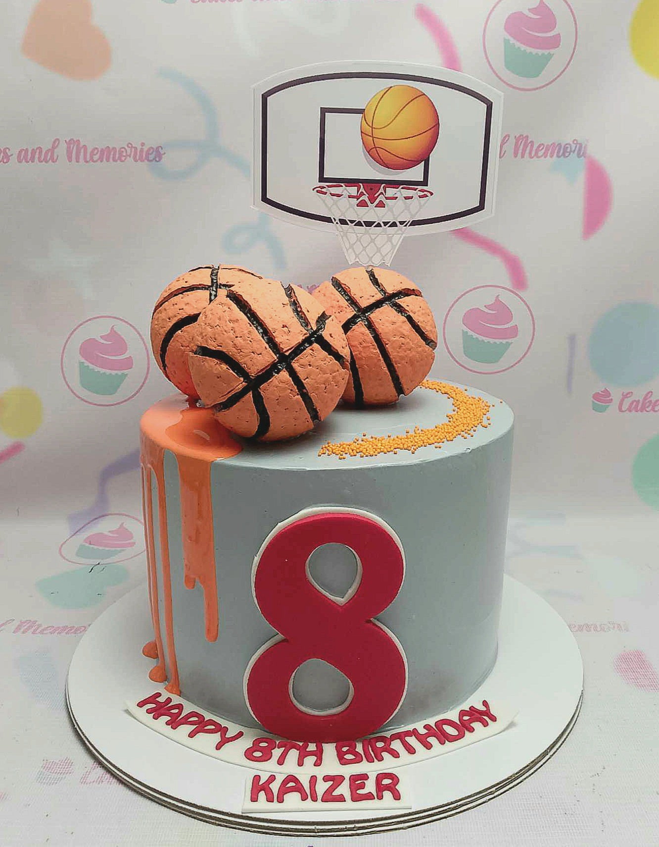 This vibrant basketball cake features a tall, single tier adorned with a playful drip design in orange and red, perfectly celebrating an 8th birthday. Decorated with sprinkles, a number 8, and printout toppers, this whimsical creation is a slam dunk for any young sports fan.