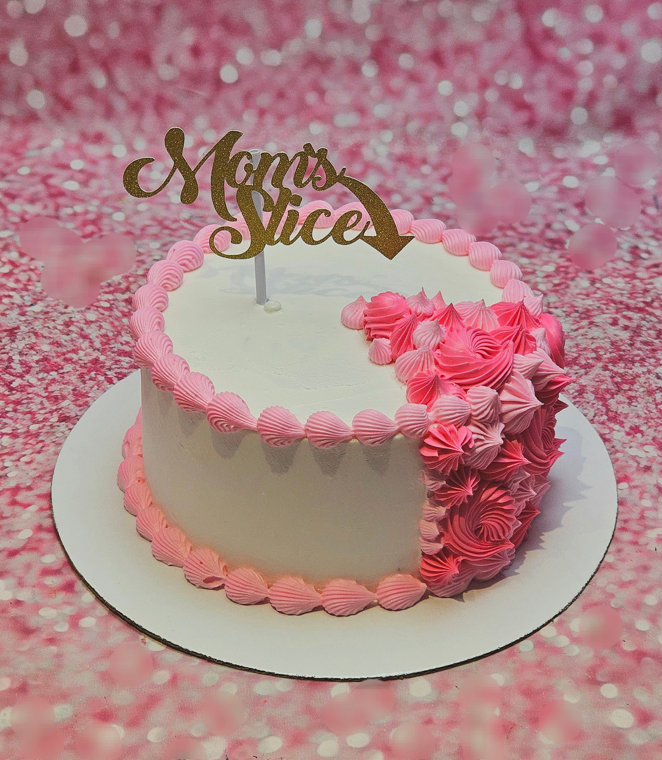 The "Mom's Slice" Cake features delicate pink icing adorned with elegant rosettes and charming printout toppers, perfect for celebrating Mother's Day. This delightful 1-layer, 1-tier cake is an ideal tribute to mothers, grandmothers, and beloved relatives.