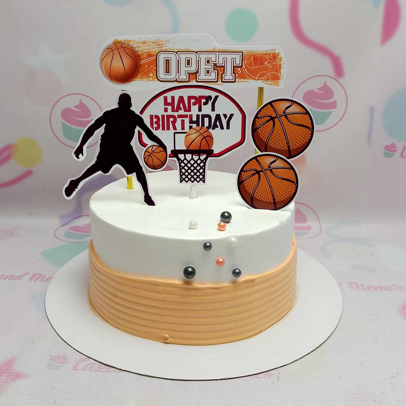 Celebrate your child's special day with this vibrant Basketball Cake featuring a clean white base and bold orange accents. Customized with fun printout toppers, this one-tier design is perfect for birthdays, whether for a brother, dad, or any sports-loving gentleman in your life.