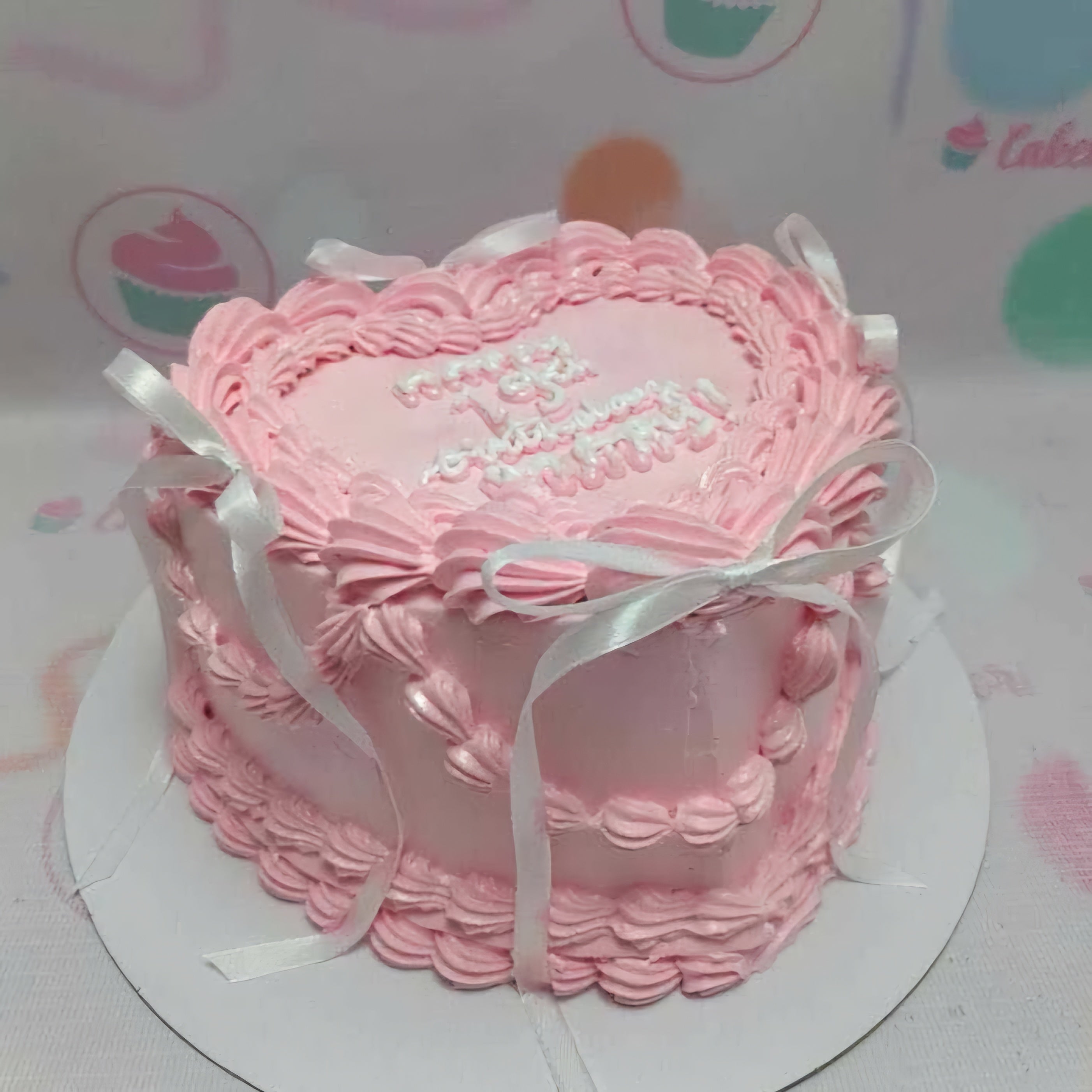 A charming vintage cake adorned in soft pink hues, perfect for a 19th birthday or anniversary celebration. Topped with heart-shaped printout toppers and finished with a delicate white ribbon bow for that special touch.