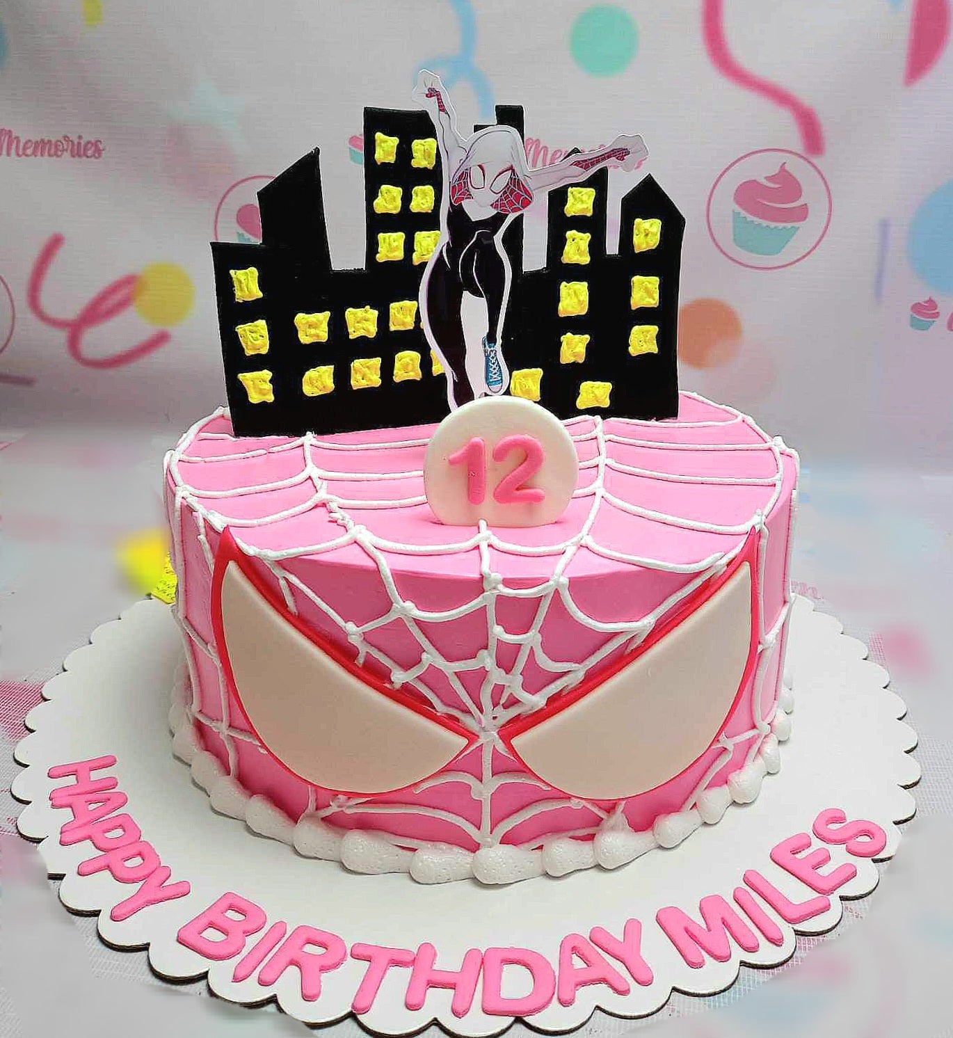 This custom Spiderman Cake features a striking pink design with Spider-Gwen and a cityscape backdrop, perfect for a 12th birthday celebration. Adorned with spider-eyes and inspired by Miles Morales, it's a one-tier masterpiece.