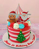 This delightful Christmas cake showcases red and white stripes with charming printout toppers of Santa Claus, a gingerbread man, and Christmas trees under a circus tent design. Adorned with swirls and sprinkles, it celebrates a special 1st birthday in style.