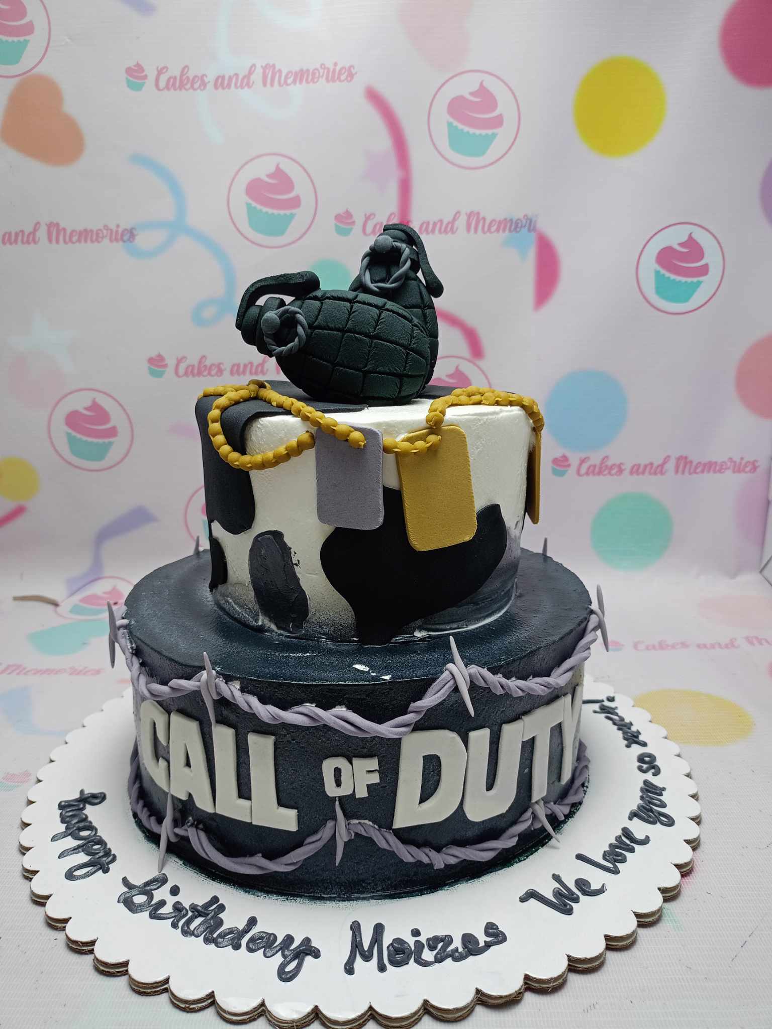 This striking two-tier military cake features a bold black and gray camouflage design, complete with an impressive edible grenade topper, perfect for any Call of Duty fan or soldier-themed birthday celebration. Customize your cake to honor the special soldier in your life with this captivating and unique design.