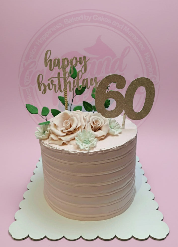 One-tier rose gold 60th birthday cake with striped buttercream, sugar roses, and gold 'happy birthday 60' toppers.