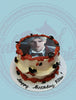 Two-tier Genshin Impact birthday cake with Dainsleif edible print, red icing, black butterflies, and 'Happy Birthday Kitten!' text.