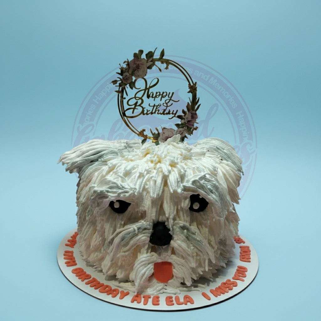 Custom dog birthday cake with white shaggy buttercream fur, black eyes & nose, orange tongue, and a 'Happy Birthday Ate Ela' topper.