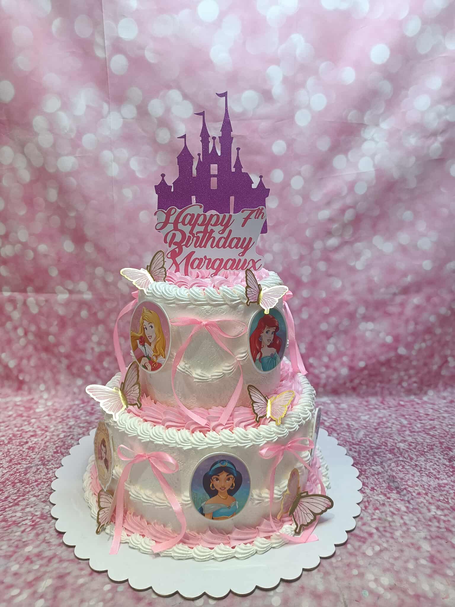 Two-tier Disney Princess 7th birthday cake for Margaux, with Aurora, Ariel, Jasmine edible prints, pink buttercream, ribbons, and butterflies.