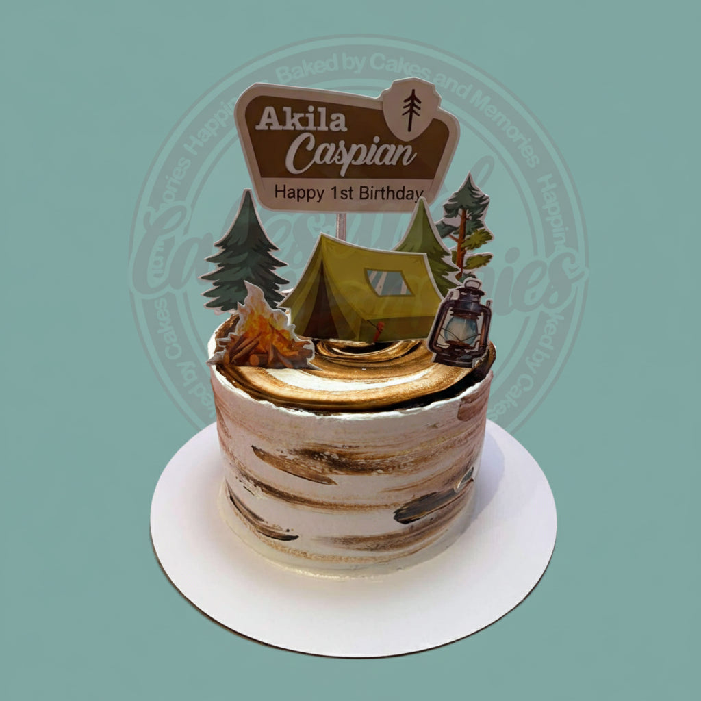 One-tier camping birthday cake with rustic brown and white buttercream, featuring a tent, campfire, trees, and 'Akila Caspian Happy 1st Birthday' topper.