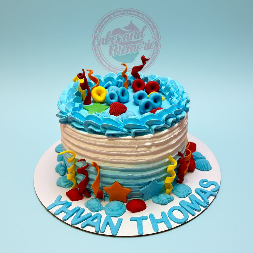 Custom buttercream Under the Sea cake, featuring "Yhvan Thomas" and colorful fondant sea elements in blue and white.
