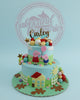 Two-tier Peppa Pig birthday cake for Carley with Peppa, George, their house, and muddy puddles in blue and green.
