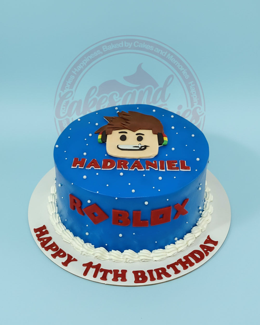 One-tier round Roblox birthday cake for Hadraniel's 11th, with blue buttercream, fondant Roblox avatar, and red text.
